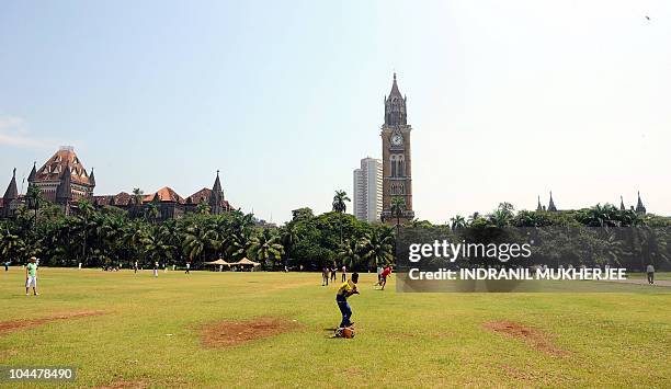 Foreign tourists play cricket with an Indian youth at the Oval maidan landmark in Mumbai near the Bombay University tower on September 27, 2010. The...