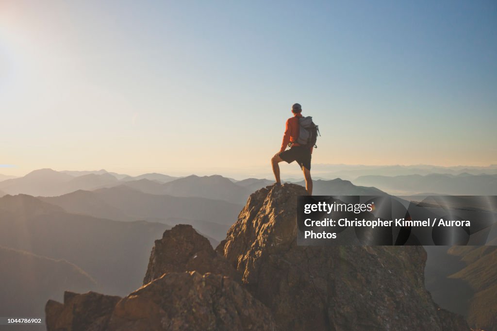 Photograph of adventurous backpacker standing on mountain peak, North Cascades National Park, Washington State, USA