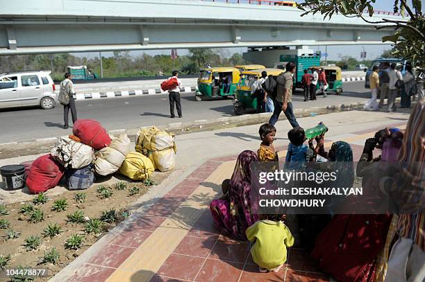 An Indian homeless family, hired to clear the pavement ahead of the Commonwealth Games, wait for a bus in New Delhi on September 27, 2010. Organisers...