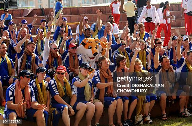 Members of the Scottish team cheer with Shera, the New Delhi Commonwealth Games mascot during the flag hoisting cermony at the Games' village in...