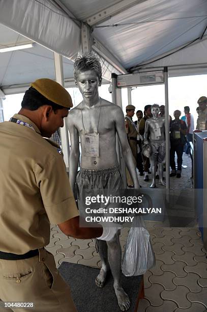 An Indian security man checks a performer at the entrance of the Commonwealth Games Village in New Delhi on September 27, 2010 prior to the flag...