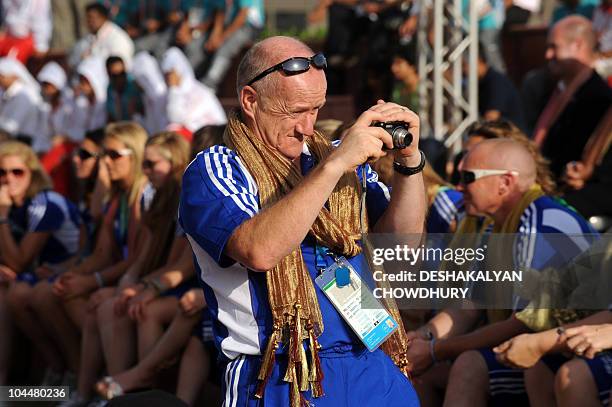 Member of the Scottish team takes a photograph during the flag hoisting cermony at the Games' village in New Delhi on September 27, 2010. The...