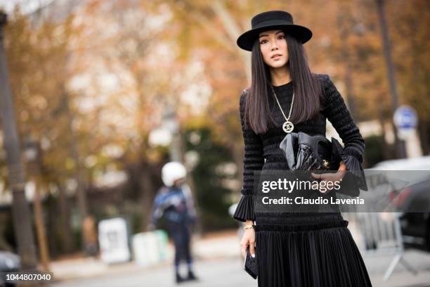 Yoyo Cao, wearing a long black dress, Chanel necklace, printed boots, Chanel black bag and black hat, is seen before the Chanel show on October 2,...