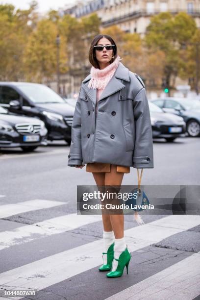 Gilda Ambrosio, wearing a pink sweater, beige mini skirt, green heels with white socks, blue bag and grey jacket, is seen before the Miu Miu show on...