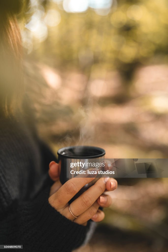 Woman picking mushrooms and drinking coffee in the forest