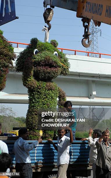Indian workers transport a decorative hedge representing Shera, the New Delhi Commonwealth Games mascot near the Games' village in New Delhi on...