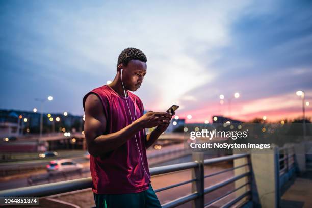 jovens africanos homens descansando após ao ar livre do treinamento, usando telefone celular - sports training - fotografias e filmes do acervo