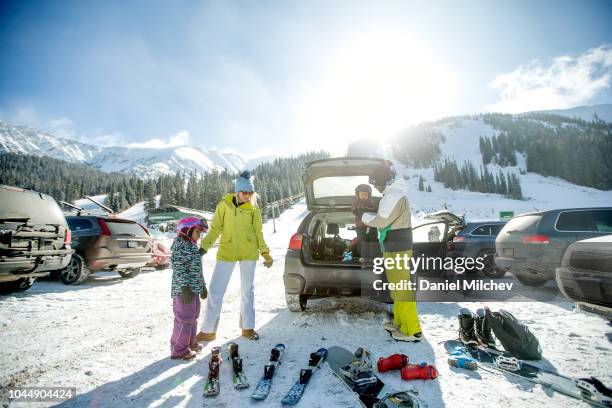 mixed race family at a parking lot unloading ski and snowboard equipment out of their car and getting the kids ready for a day on the mountain. - keystone stock pictures, royalty-free photos & images