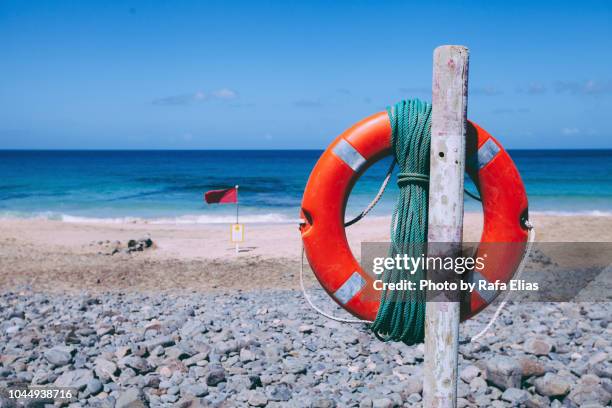 life preserver and red flag on the beach - red flag warning stock pictures, royalty-free photos & images