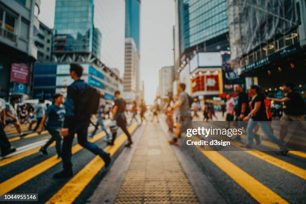 defocused image of busy commuters crossing the street in downtown district against contemporary corporate skyscrapers - hong kong mass transit fotografías e imágenes de stock