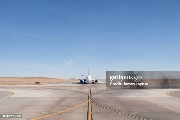 straight on view of a jet airplane taxing on an airport runway - pista di atterraggio foto e immagini stock