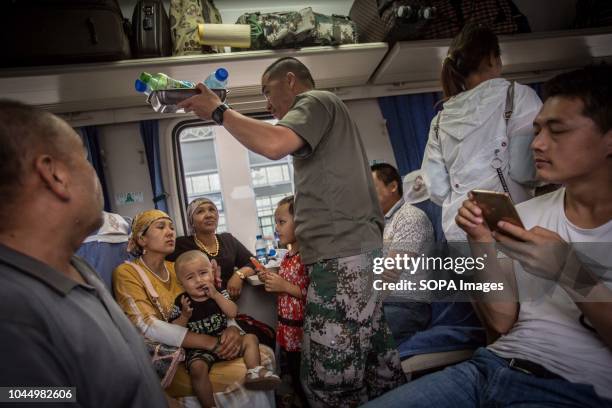 Uyghur and Han Chinese seen buying food at a local vendor inside a train from Hotan to Kashgar in Xinjiang Uyghur Autonomous Region in China. Kashgar...