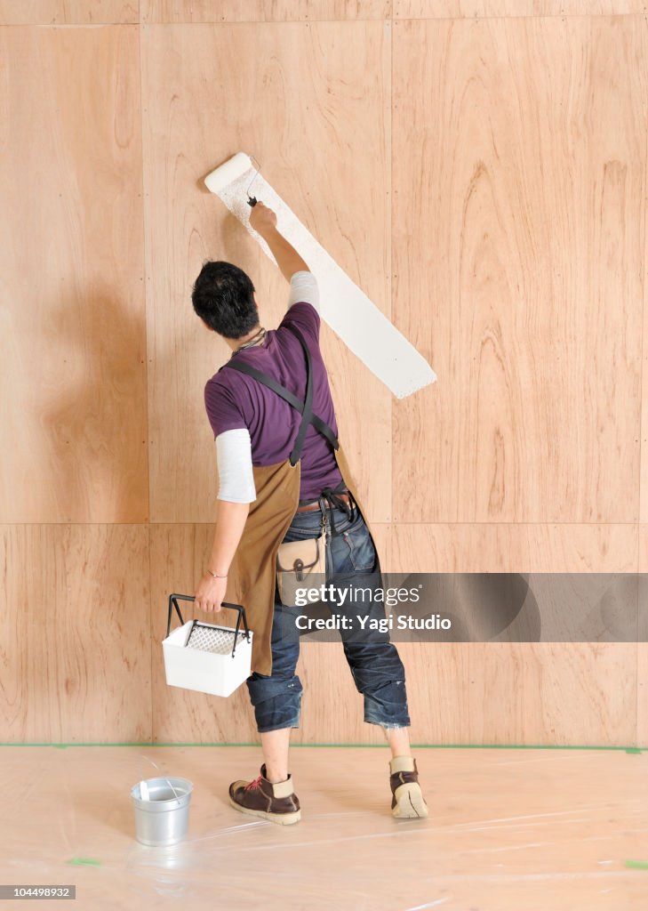 The man painting a wall, rear view