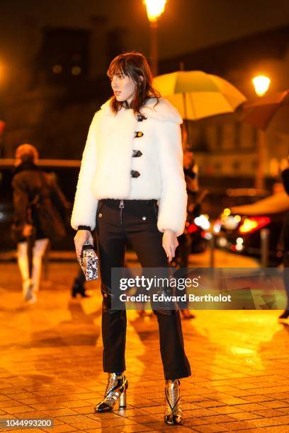 Teddy Quinlivan wears a white fluffy coat, black flare pants, a clutch, shiny shoes, outside Vuitton, during Paris Fashion Week Womenswear...