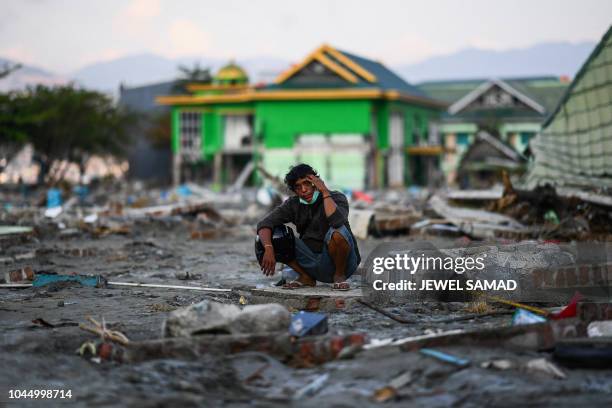 An earthquake-affected man sits on the rubble of a house in Palu in Indonesia's Central Sulawesi on October 3 after an earthquake and tsunami hit the...