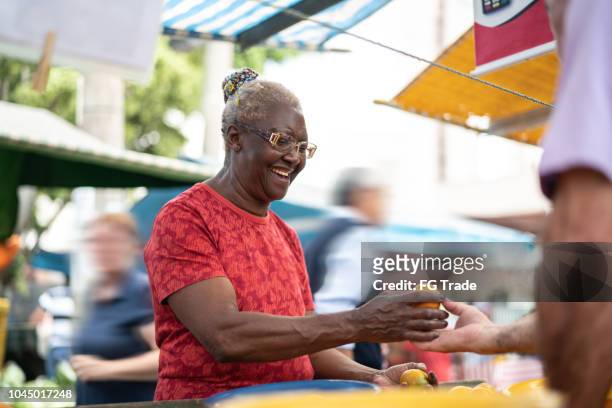 senior african ethnicity woman buying fruits on farmers market - rio de janeiro street stock pictures, royalty-free photos & images