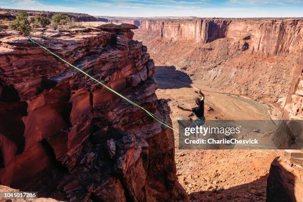 man catching balance on the slack-line - high-line with spectacular view behind - slackwire stock pictures, royalty-free photos & images