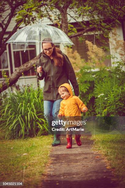 mutter und sohn in regenmäntel wandern in regen - mother protecting from rain stock-fotos und bilder