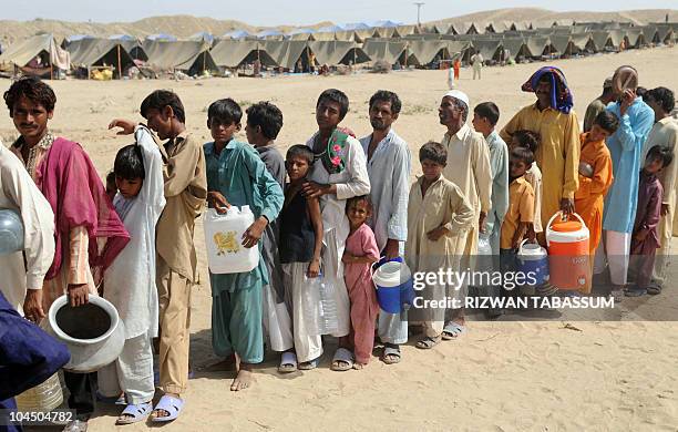 Pakistanis displaced by floods queue for water at an army-run makeshift tent camp in Sehwan, Sindh province, on September 22, 2010. Torrential rain...