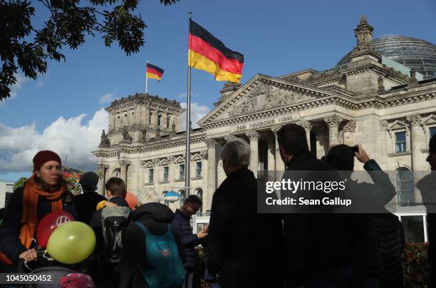 Visitors walk in front of the Reichstag under German flags during celebrations to mark German Unity Day on October 3, 2018 in Berlin, Germany. Unity...