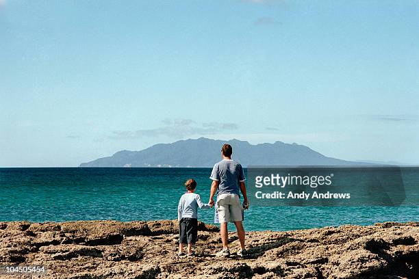 father and son look out to sea - great expectations stock pictures, royalty-free photos & images