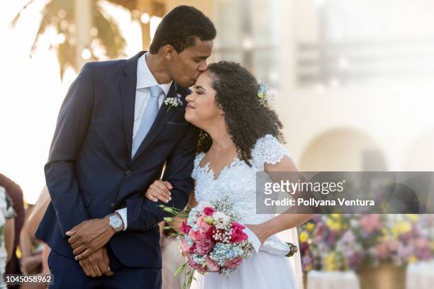 groom kisses his bride on the forehead - african americans getting married stock pictures, royalty-free photos & images