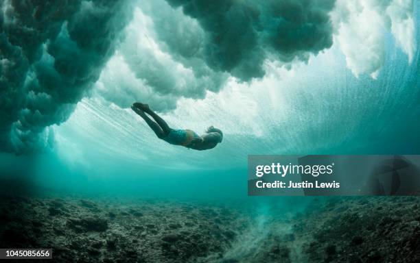 young man free dives beneath turbulent ocean, exploring coral reefs - man underwater stock pictures, royalty-free photos & images