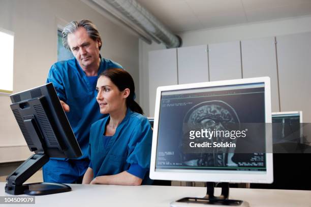 doctor and nurse looking at mr images - odense stock-fotos und bilder