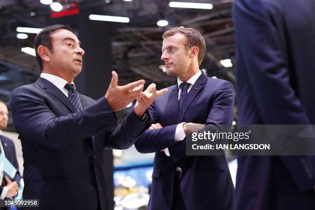 French President Emmanuel Macron listens to CEO of French car maker Renault Carlos Ghosn during an official visit at the Paris auto show in Paris, on...