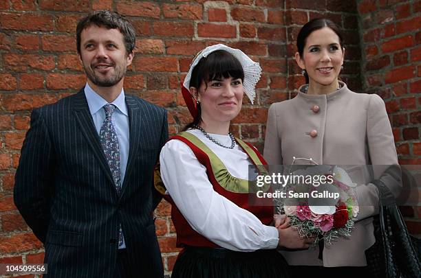 Danish Crown Prince Frederik and Danish Crown Princess Mary , who is pregnant with twins, receive flowers from a woman wearing local, traditional...