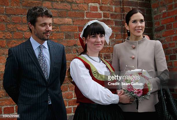 Danish Crown Prince Frederik and Danish Crown Princess Mary , who is pregnant with twins, receive flowers from a woman wearing local, traditional...