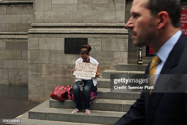 Business man walks by a homeless woman holding a card requesting money on September 28, 2010 in New York City. A new report released by the U.S....