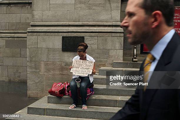 Business man walks by a homeless woman holding a card requesting money on September 28, 2010 in New York City. A new report released by the U.S....