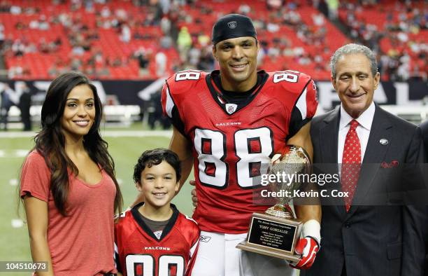 Tony Gonzalez of the Atlanta Falcons poses with his wife October, son Nikko and Owner and CEO Arthur Blank after receiving an award for his 1000th...