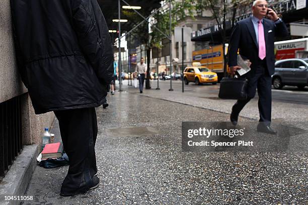 Businessman walks by a homeless woman holding a card requesting money on September 28, 2010 in New York City. A new report released by the U.S....