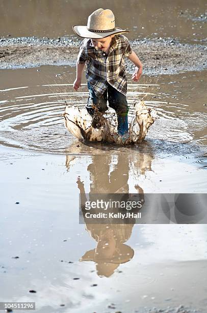 little boy jumping through mud puddle - wellington boots stock pictures, royalty-free photos & images