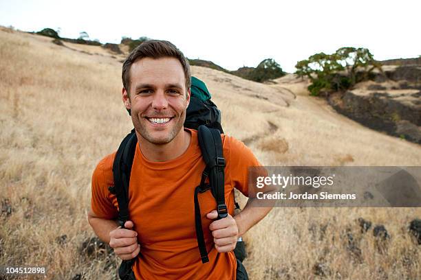 male smiles while hiking in the outdoors. - mid adult stock pictures, royalty-free photos & images