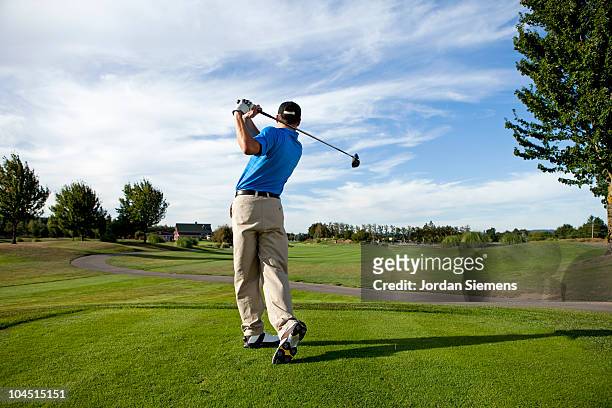 man hitting a ball on the golf course. - golfing stockfoto's en -beelden
