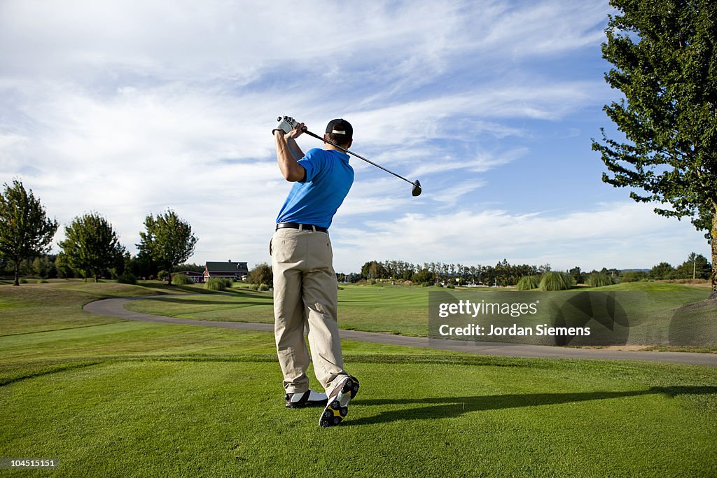 Man hitting a ball on the golf course.