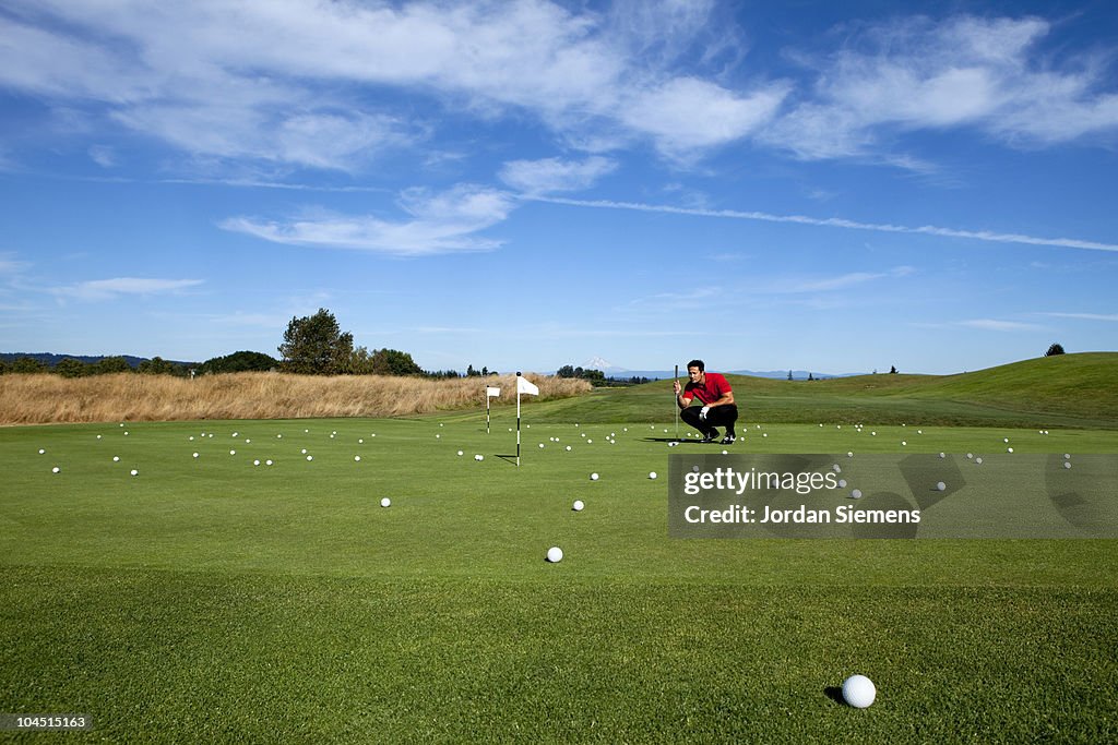Man lining up a putt while golfing.