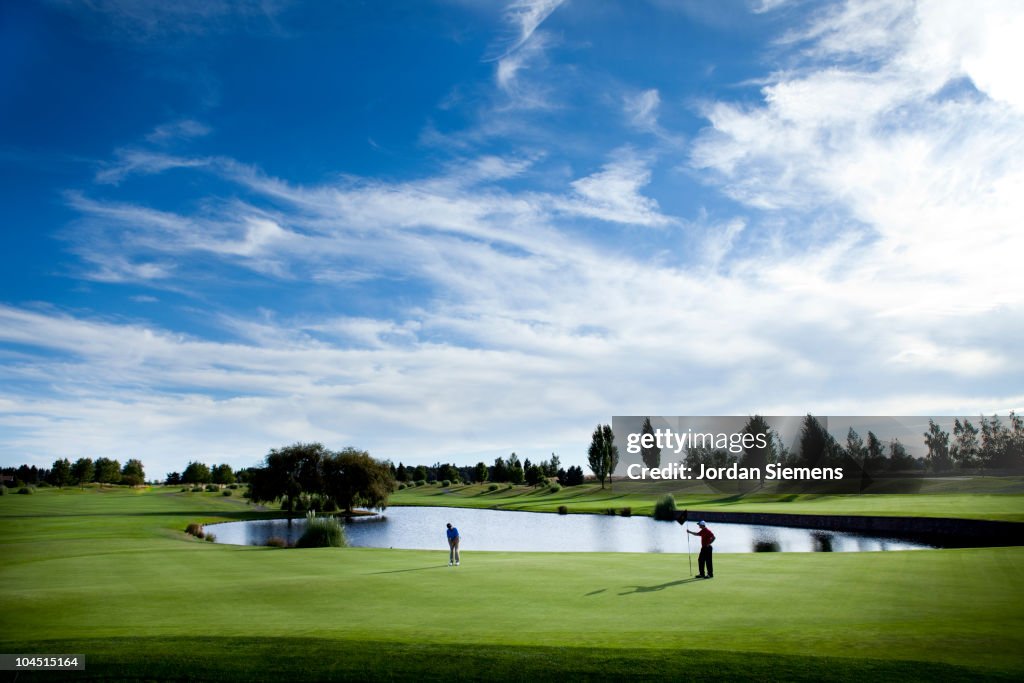 Two men golfing on a green.