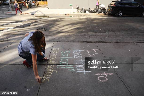 Sophie Sandberg uses colored chalk to draw a quote on the sidewalk from a catcall made towards a woman on October 3, 2018 in New York City. Victims...