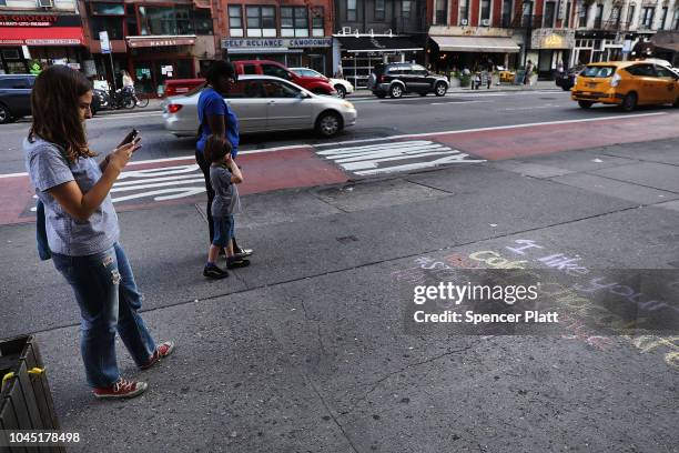 Sophie Sandberg takes a picture after useing colored chalk to draw a quote on the sidewalk from a catcall made towards a woman on October 3, 2018 in...