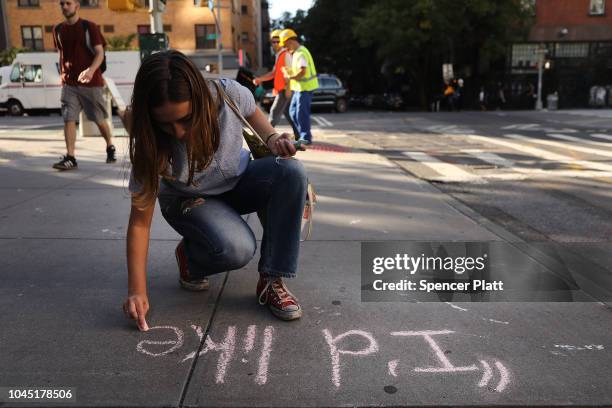 Sophie Sandberg uses colored chalk to draw a quote on the sidewalk from a catcall made towards a woman on October 3, 2018 in New York City. Victims...