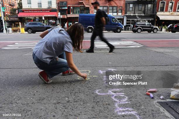 Sophie Sandberg uses colored chalk to draw a quote on the sidewalk from a catcall made towards a woman on October 3, 2018 in New York City. Victims...