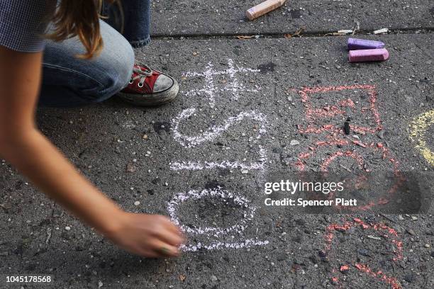 Sophie Sandberg uses colored chalk to draw a quote on the sidewalk from a catcall made towards a woman on October 3, 2018 in New York City. Victims...