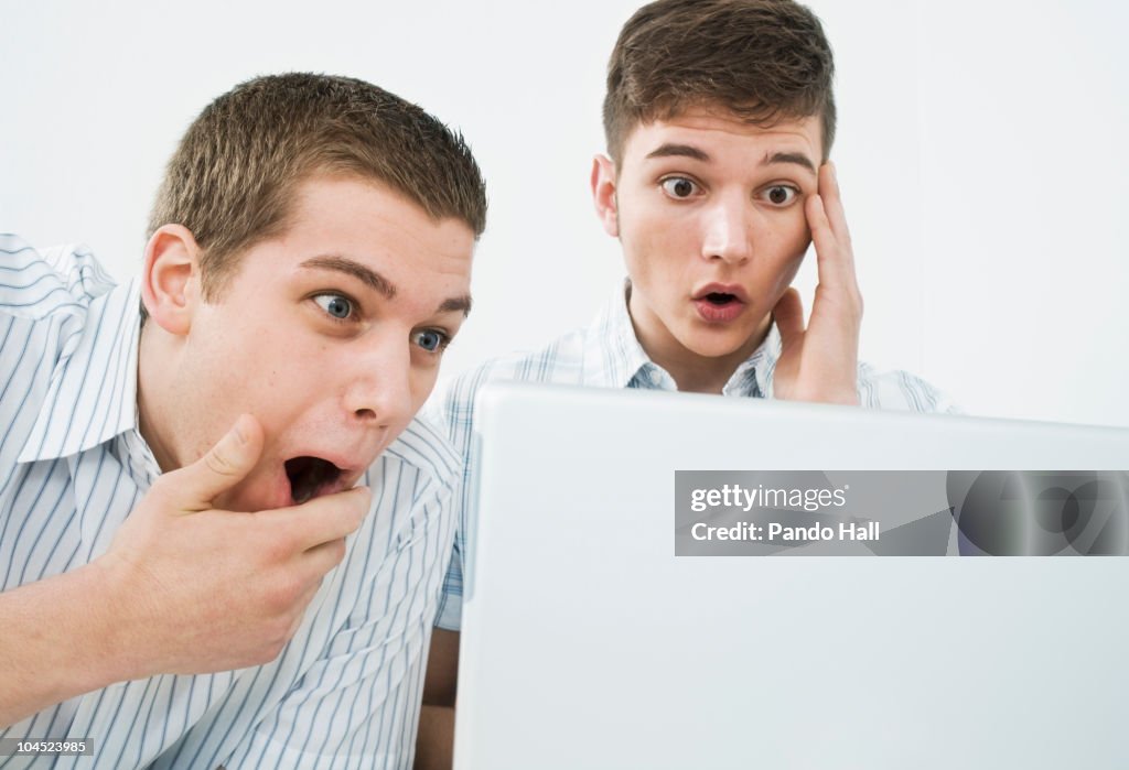 Two young men with laptop, laughing