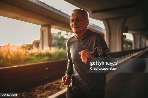 senior jogging in the city - fitness armband stock pictures, royalty-free photos & images