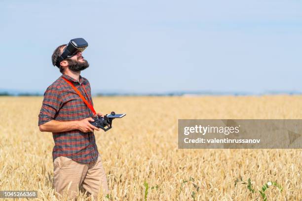 agricoltore che vola un drone su un campo e utilizza cuffie vr - drone agriculture foto e immagini stock