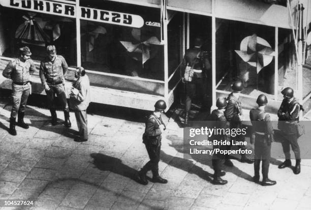 Polish troops check a man's papers while another enters a shop, during anti-government street demonstrations by supporters of the Polish trade union...